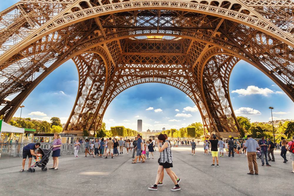 Turistas caminando bajo la Torre Eiffel